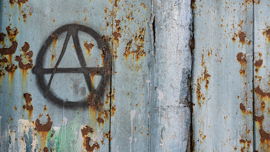 black sign of anarchy on an old fence. culture of anarchists, punks and street protests. Symbol of Anarchy painted on a wall